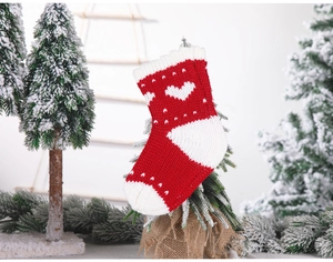 Detail of red and white knitted Christmas stocking with heart patterns and soft textures