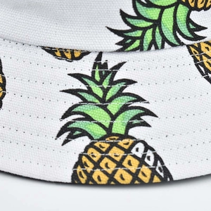 Close-up of double-stitched seams and vibrant pineapple patterns on white bucket hat