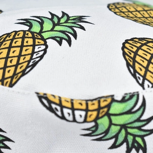 Close-up of white canvas sun hat fabric with vibrant yellow pineapple print pattern
