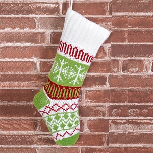 Detail of red and white knitted Christmas stocking with snowflake patterns on brick wall