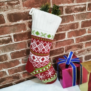 Classic knitted Christmas stocking with red and white Nordic patterns on a brick background