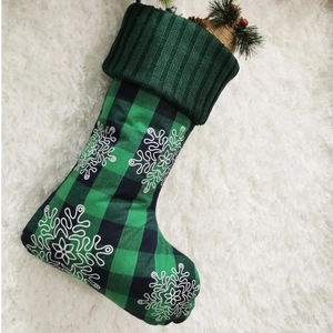 Detail of green plaid 18-inch Christmas stocking with snowflake and red berries filling