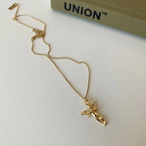 Macro detail of gold angel pendant necklace showing fine Cupid wings and clasp
