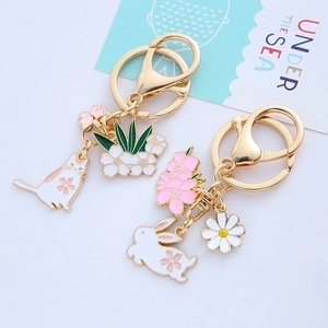 Cute enamel rabbit and cat keychain pendants with gold metal hardware on white background