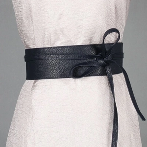 Close-up of black wide waist belt with elegant bow tie knot on textured dress