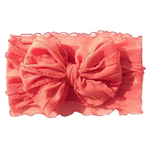 Detail of coral lace baby headband featuring large layered bow and elastic fabric