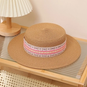 Detail of flat top straw hat with pink ethnic pattern band on wooden shelf