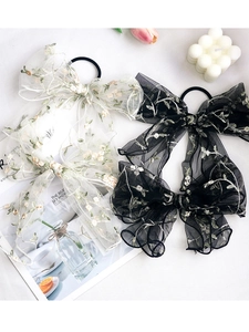 Close-up of elegant floral embroidered organza bow clips in cream and black tones