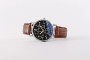 Detail of blue quartz watch dial with silver case and brown crocodile leather strap