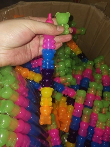 Detail of colorful stackable bear highlighters held in hand within a warehouse storage