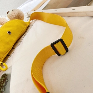 Détails de la bandoulière en nylon noir et des attaches sur le sac en toile jaune