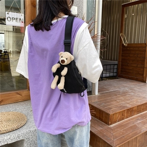 Vue extérieure d'un sac de poitrine en toile noire avec un ours en peluche beige