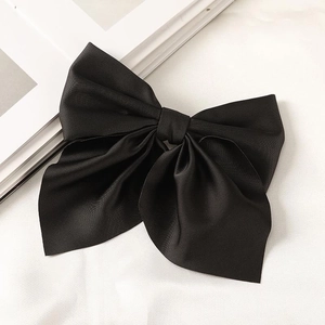 Close-up of a large black satin bow hair clip featuring a layered design and smooth texture