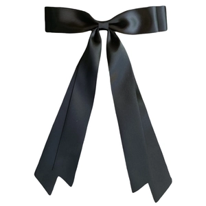 Close-up of a glossy black satin ribbon bow hair clip with elegant balletcore style