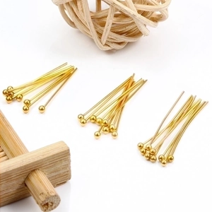 Polished gold ball head pins for jewelry making shown on a natural wood surface