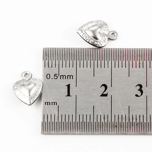 Polished silver heart pendant charm with 10mm measurement on a steel ruler scale