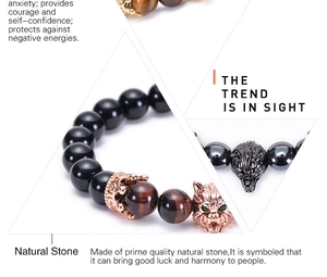 Macro detail of natural tiger eye and onyx beads with rose gold crown and wolf charms