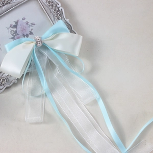 Detail of light blue and white organza ribbon bow with pearls and rhinestones decoration