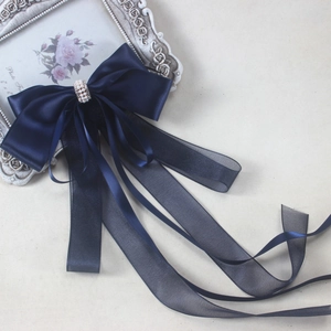 Close-up of deep blue satin bow hair clip with ribbons and pearls on a vintage frame