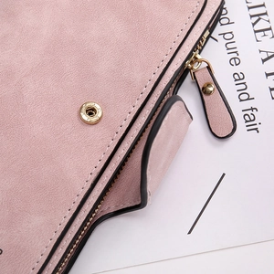 Dettaglio del portafoglio in pelle opaca rosa con cuciture di pregio e cerniera dorata