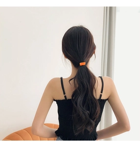 Detail shot of a bright orange seamless elastic hair tie securing a ponytail on a model
