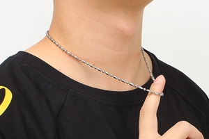 Close-up of a silver stainless steel ball and oval link chain worn around the neck