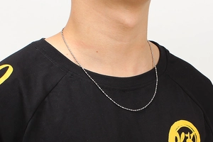 Close-up of minimalist silver stainless steel bead chain necklace worn on collarbone