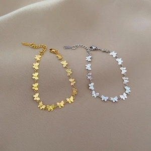 Titanium steel butterfly link bracelets in gold and silver on champagne silk background