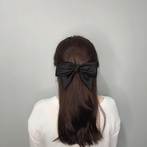 Elegant large black satin bow hair clip for women styled on long dark hair