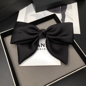 Close-up of black satin oversized bow hair clip in premium branded gift packaging box