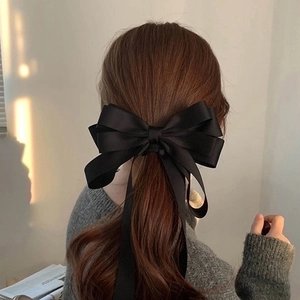 Elegant large black satin bow hair clip with long ribbons on a ponytail