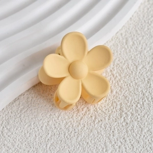 Detail of matte yellow flower hair claw clip with a five-petal design on white background