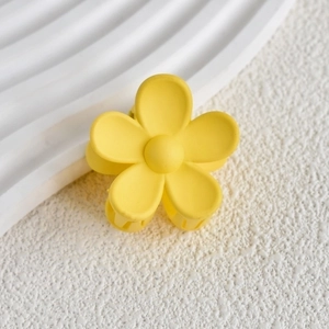 Detail of yellow matte flower hair claw clip with a five-petal design on white tray