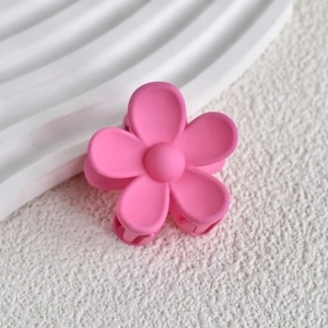 Close-up of pink matte flower hair claw clip with delicate five-petal floral design