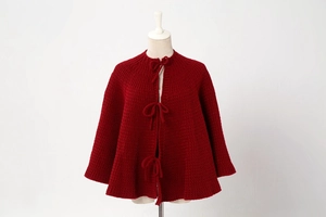Detailed knit texture of large red Christmas tree skirt on a mannequin display