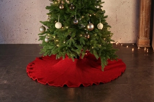 Macro detail of red knitted Christmas tree skirt with ruffled edges and thick yarn texture