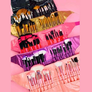 Multiple colorful makeup brush sets with matching storage waist bags on pink background