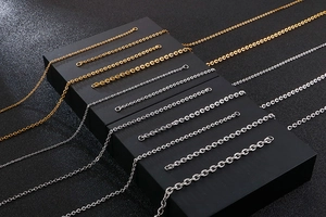 Detailed close-up of various stainless steel O-chain necklaces in gold and silver finishes