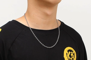 Detail of a minimalist silver O-chain necklace on a model with a dark t-shirt background