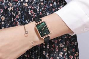 Close-up of vintage square green dial watch with gold case and black leather strap