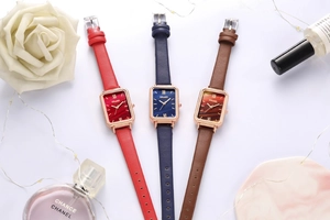 Detailed view of three square women watches with red, blue, and brown leather straps