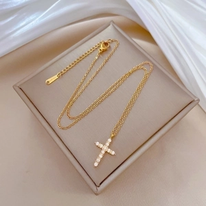 Titanium steel cross necklace with crystal pendant in gold finish on a soft display stand