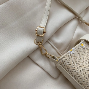 Detail of woven straw texture with beige leather trim and golden metal clasp on bucket bag