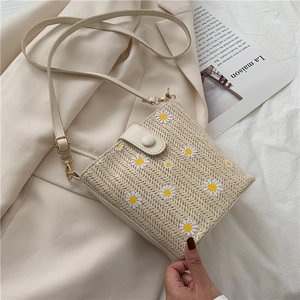 Detail of cream woven bucket bag with daisy patterns on beige fabric background