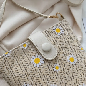 Close-up of straw bucket bag with white daisy embroidery and premium PU leather trim