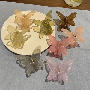 Elegant butterfly hair claw clips in pastel macaron colors on a ceramic dish