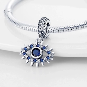 Silver evil eye charm with blue gemstones on snake chain bracelet in studio setting