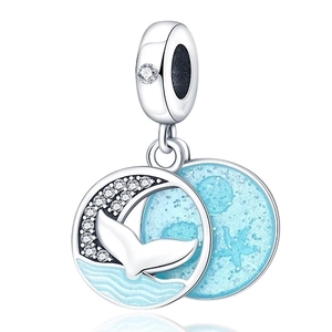 Macro detail of silver ocean charm with blue enamel dolphin and whale tail