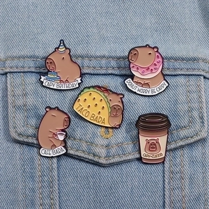 Cartoon Capybara enamel pin set with food themes pinned on blue denim fabric
