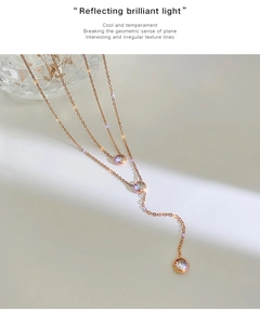 Dettaglio della collana a due strati in oro rosa con pendenti di cristallo su fondo bianco